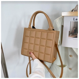 Detail showing the quilted rhombus pattern and leather handle of the camel square handbag