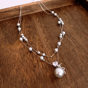 Détail du collier double rang avec pendentif coeur en zircon et perle grise
