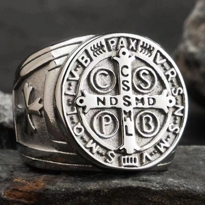Macro shot of silver stainless steel Saint Benedict medal ring on a dark rock surface