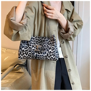Detail of leopard print shoulder bag with gold T-clasp and chain strap on a trench coat