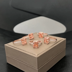 Dettaglio di cinque anelli in oro rosa con pietre rettangolari champagne su espositore