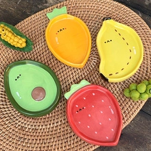 Detailed view of four small ceramic dessert plates in fruit and vegetable shapes on rattan