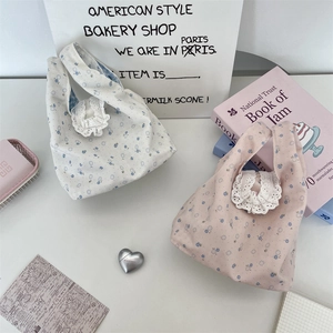 Dettaglio della borsa tote in tela floreale con elegante bordo in pizzo bianco
