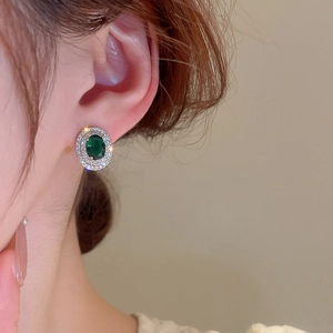 Close-up of elegant emerald green zircon earrings worn by a model in vintage style