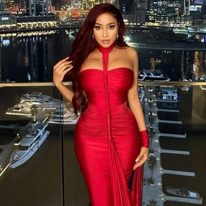 Elegant red backless halter satin dress with city skyline background for formal banquet