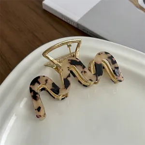 Detail of French vintage metal claw clip with amber acetate wave pattern on a ceramic dish