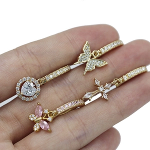 Detail of four gold navel jewelry designs with butterfly, cross and heart cubic zirconia