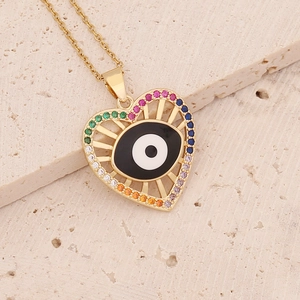 Golden heart necklace with colorful zircon evil eye pendant on marble surface