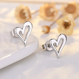 Minimalist hollow heart stud earrings in 18K gold plated silver on decorative background