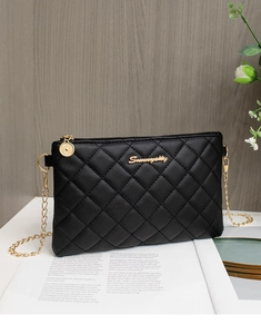 Détail du sac bandoulière matelassé noir avec chaîne dorée et logo sur table