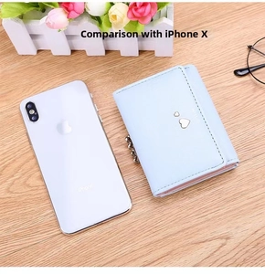 Short light blue tri-fold wallet with heart detail next to iPhone X for size comparison