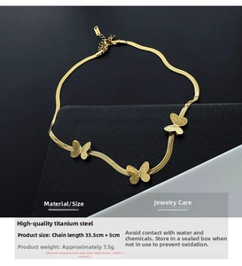 Détail du collier papillon en acier titane avec une élégante chaîne serpent dorée