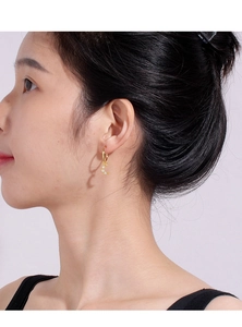 Close-up of gold hoop earrings with hollow moon and star pendants with zircon inlay