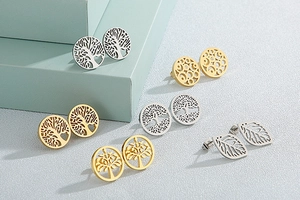 Detail of tree of life and leaf pattern stud earrings on minimalist blue geometric stands