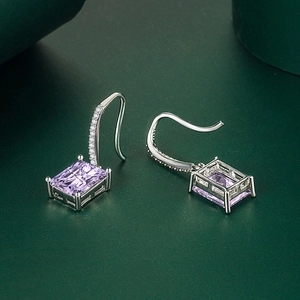 Close-up of rectangular purple zircon earrings with silver hooks and micro-pave accents