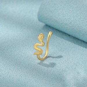 Macro shot of gold snake-shaped nose ring with detailed scale texture on blue surface