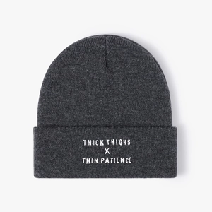 Close-up of dark grey knitted beanie featuring white thick thighs thin patience embroidery