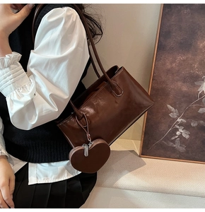 Model wearing a dark brown vintage Boston bag with a matching heart-shaped pendant