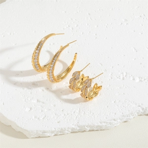 Elegant gold C-shaped and leaf zircon hoop earrings set on a textured white stone base