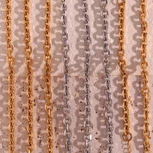 Polished 18K gold and silver stainless steel cable chains on textured stone background