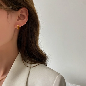 Minimalist gold U-shaped beaded earrings with textured finish worn by a model