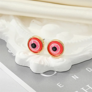 Macro shot of evil eye stud earrings with red glitter resin on a white textured base