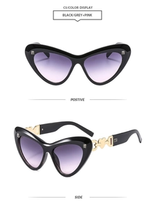 Detail of heart cat-eye sunglasses with gold metal accents and grey-pink gradient lenses