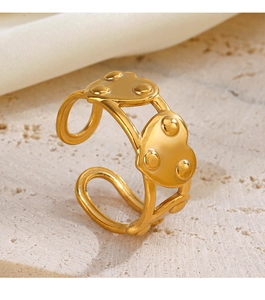 Gros plan d'une bague coeur dorée avec détails perlés sur pierre et tissu doux