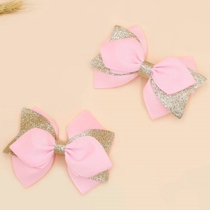 Pink ribbon and gold glitter bow hair clips for kids in a sweet minimalist flat lay style