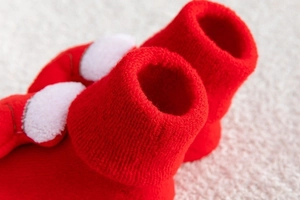 Close-up of red Christmas baby knit sock with soft white plush cloud and ribbed cuff detail