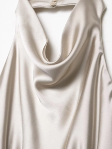 Detail of elegant champagne satin dress featuring a cowl neck and halter closure