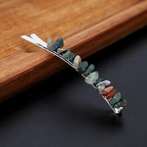 Macro detail of silver hair clip with natural colorful stone chips on dark background