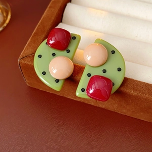 Nahaufnahme grüner Harzohrringe mit Polka Dots und roten quadratischen Akzenten in Box