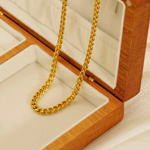 Polished 18K gold plated stainless steel Cuban link chain necklace on a jewelry box