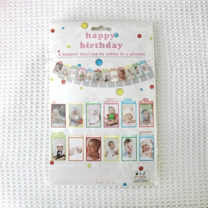 Detail of baby first birthday gold glitter photo banner packaging with 12 month paper flags