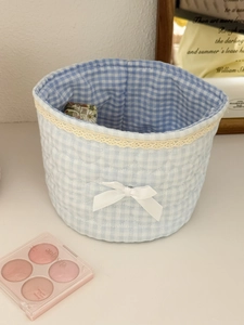 Detail of blue plaid fabric storage basket with lace trim and white ribbon bow