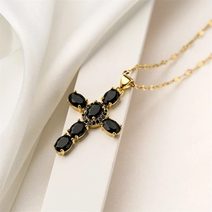 Detail of vintage gold cross necklace with black zircon stones on silk background