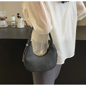 Detailed view of dark grey crescent shoulder bag with silver hardware and matte leather texture