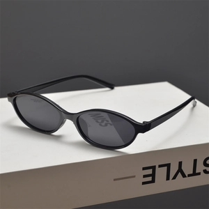 Detail view of oval black y2k sunglasses on a minimalist display stand with soft lighting