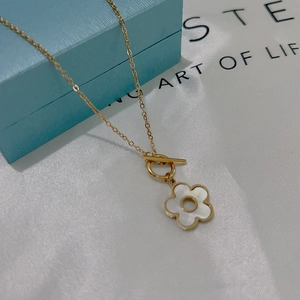 Detail of gold necklace with white shell flower pendant and functional toggle clasp design