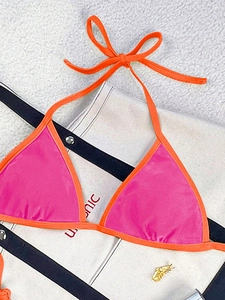 Detailed flat lay of pink and orange colorblock halter bikini top on white textured surface