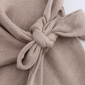 Detailed close-up of khaki knit fabric featuring a soft bow knot detail and fine texture