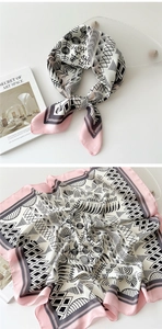 Close-up of square silk scarf with floral print and pink border on a glass tray
