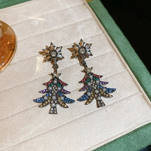 Close-up of snowflake and Christmas tree earrings with colorful crystals and pearls