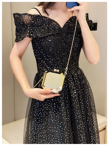 Octagonal gold metal clutch bag with chain strap styled with a black sequin evening dress
