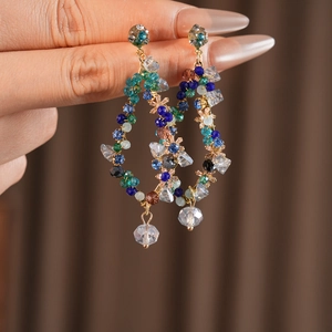 Detailed close-up of vintage gold wire earrings with colorful beads and clear pendant