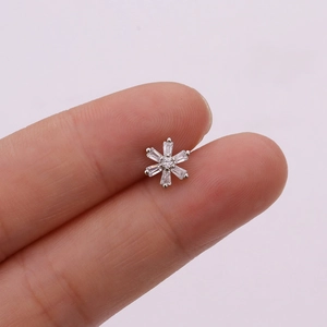 Macro shot of silver snowflake ear stud with clear zircon held between fingers