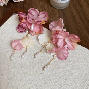 Detailed macro view of pink floral earrings with silk petals and teardrop pearls