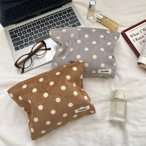 Flat lay of vintage polka dot corduroy pouches with cosmetics and metal zipper detail