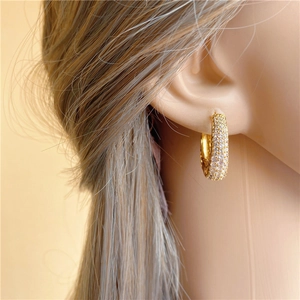 Close-up of gold U-shaped hoop earrings with sparkling micro-pave diamond inlay
